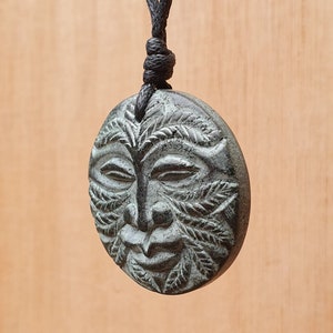 以下が含まれることがあります： 黒い紐に、自然の精霊のような彫刻が施された緑色の石のペンダント