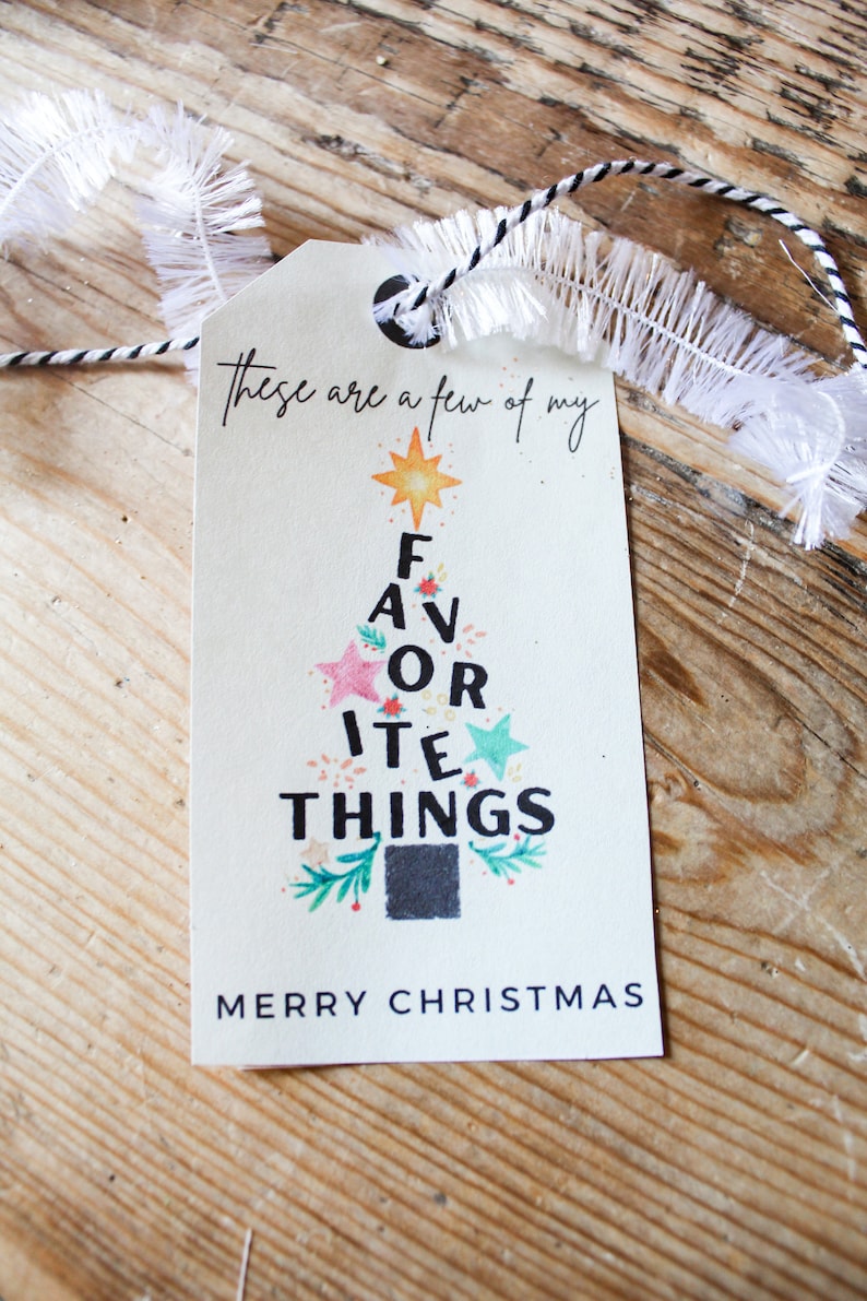 Op de afbeelding: Een wit cadeau-etiket met een kerstboomontwerp. De boom is gemaakt van de woorden "These are a few of my favorite things" en heeft een ster bovenop. Het etiket zegt ook "Merry Christmas".
