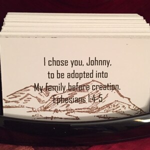 May include: A white card with a brown mountain scene and the text "I chose you, Johnny, to be adopted into My family before creation. Ephesians 1:4-5".