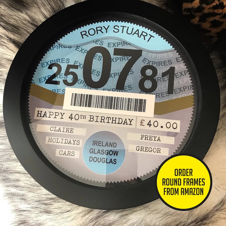 May include: A black and white round framed sign with a blue background. The sign says "RORY STUART" and "HAPPY 40TH BIRTHDAY &pound;40.00". The sign also has a barcode and a number "250781".