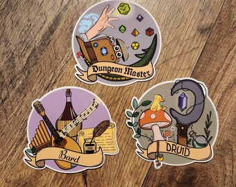 May include: Three round stickers with illustrations and text. The first sticker is purple with a lute, a flute, a quill and inkwell, and the text "Bard". The second sticker is gray with a hand holding a dice, a book, and the text "Dungeon Master". The third sticker is green with a duck on a mushroom, a staff with a crescent moon, and the text "Druid".