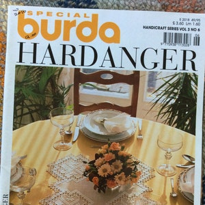 May include: A Special Burda Hardanger handicraft magazine, volume 3 number 6, featuring a yellow tablecloth with a white embroidered centerpiece, crystal glassware, and a floral arrangement. The cover text includes A TREASURE TROVE FOR BEGINNERS AND EXPERTS 80 LOVELY EMBROIDERY PROJECTS TO CHOOSE FROM Complete with charts and 6-page illustrated course.