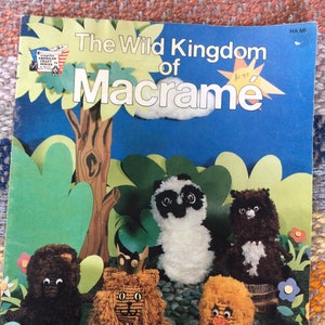 May include: A book titled "The Wild Kingdom of Macrame" with a number "#1-76" written on the cover. The book features a colorful illustration of a jungle scene with a variety of animals made from macrame, including a lion, a panda, a bear, and a bird.