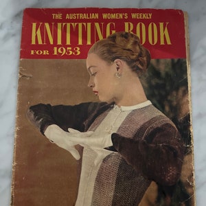 May include: A vintage knitting book cover featuring a woman wearing a knitted sweater. The cover is red with the title "Knitting Book for 1953" in yellow lettering. The text "For Adults and Children" is printed in blue at the bottom of the cover.