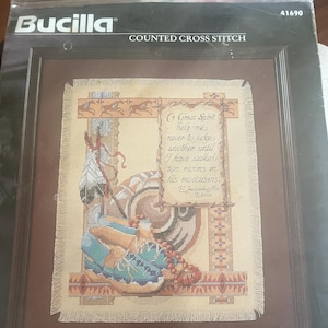 May include: Framed counted cross-stitch kit titled "Walk In My Moccasins." The artwork depicts a Native American figure with a headdress and moccasins, with the text "O Great Spirit help me..." The finished piece measures approximately 28.6cm x 36.8cm.