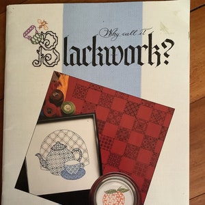 May include: The book cover for "Why call it Blackwork?" displays a black, white, and blue design with a framed illustration of a teapot and teacup. A small, round, wooden-framed image of an orange is also visible. The author's name, Marion Scoular, is printed at the bottom.