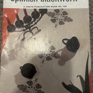 Peut inclure: Une couverture de livre vintage intitulée "modern Spanish blackwork". La couverture présente un chandelier noir avec des bougies allumées, des objets décoratifs noirs et des motifs floraux. Le livre est une publication Coats, n° 755.