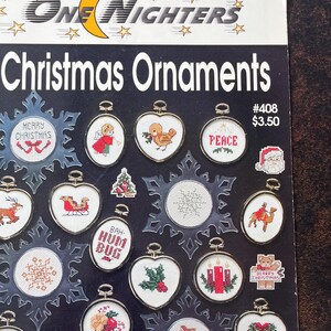 May include: A black and white booklet with the title "One Nighters 28 Christmas Ornaments" and a colourful illustration of 28 different Christmas ornaments. The ornaments are all in a circle and include designs such as a reindeer, a snowman, a Christmas tree, and a stocking.