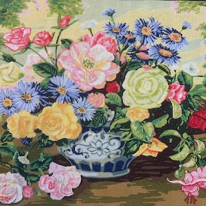 以下が含まれることがあります： 青と白の模様が入った花瓶に生けられた花の刺繍用キャンバス。ピンク、黄色、青の花と緑の葉が描かれています。上部に「COLLECTION D'ART」、下部に「MADE IN EU 100% COTTON」という文字がプリントされています。