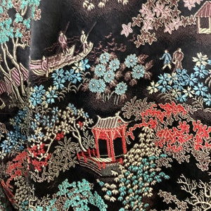 May include: Black fabric with an intricate embroidered design featuring a traditional Japanese garden scene with trees, flowers, and a pagoda. The design is in shades of blue, green, red, and gold.