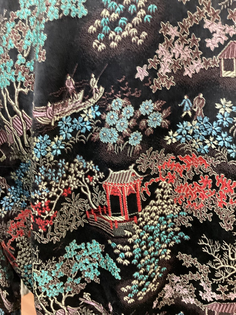 May include: Black fabric with an intricate embroidered design featuring a traditional Japanese garden scene with trees, flowers, and a pagoda. The design is in shades of blue, green, red, and gold.