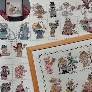 Può includere: Un motivo a punto croce con numerosi piccoli orsetti in vari abiti e pose. L'immagine include un punto croce incorniciato e una copertura per bottiglia di vino con un design a orsetto. Il testo "50 Tiny Teddies" è visibile.