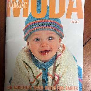 May include: A magazine titled MODA IMPACT ISSUE 4 featuring a baby wearing a blue knit hat with a multi-colored striped brim and a white knit cardigan with a blue collar and colorful yarn accents. The cover text reads 66 FABULOUS HAND KNITS FOR BABIES.