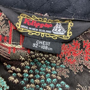May include: A black label with gold trim and the text "Klippers Made in New Zealand" with a ship logo. Below the label is a white tag with the text "CHEST 92-108 cm".