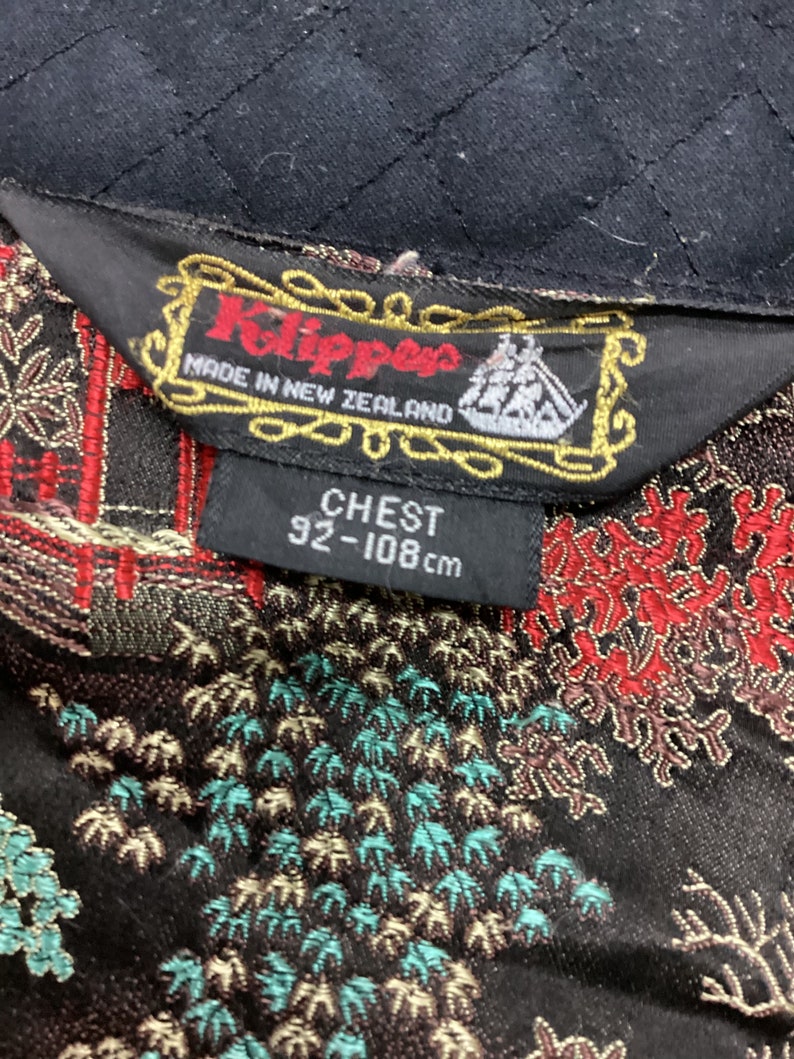 May include: A black label with gold trim and the text "Klippers Made in New Zealand" with a ship logo. Below the label is a white tag with the text "CHEST 92-108 cm".
