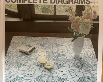 May include: A book cover titled ONDORI CROCHET LACE WITH COMPLETE DIAGRAMS featuring a white crocheted tablecloth with a floral pattern, a white vase with light pink flowers, two small glass containers, and a small rectangular box on top.