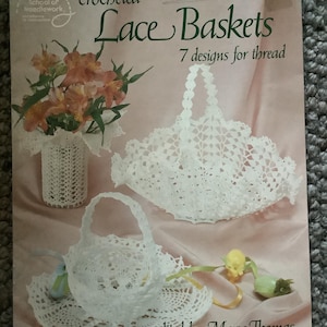 May include: A book cover featuring crocheted lace basket designs. The title "Lace Baskets" is in green script, with "7 designs for thread" below. The cover includes images of white crocheted baskets and a vase with flowers. Edited by Mary Thomas.