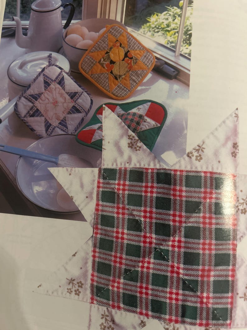 Może przedstawiać: Kolekcja kwadratowych pikowanych łapek kuchennych z wzorami gwiazd w r&oacute;żnych kolorach, w tym czerwone, zielone, białe i pomarańczowe wzory w kratę oraz kwiatowe. Łapki są prezentowane obok białego czajnika, miski z jajkami i miski do mieszania.