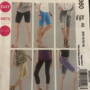May include: McCall's M6360 sewing pattern envelope featuring six variations of knit leggings and shorts in various lengths and colours, including black, blue, patterned, tan, and grey with purple side stripes, labelled with sizes A5 6-10-12-14.