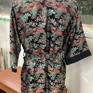 May include: A black silk robe with a colorful floral and pagoda print. The robe has a tie belt and long sleeves.