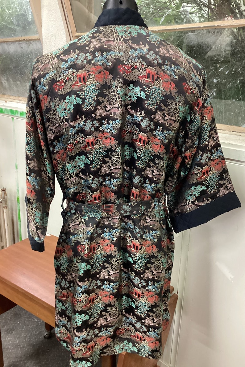 May include: A black silk robe with a colorful floral and pagoda print. The robe has a tie belt and long sleeves.
