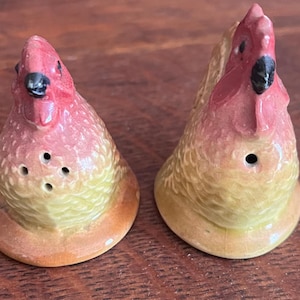 Puede incluir: Un par de saleros y pimenteros de cerámica con forma de gallina. Los saleros y pimenteros están pintados con un degradado de colores, incluyendo rojo, amarillo y naranja. Cada uno tiene un pico negro y tres agujeros para dispensar sal o pimienta.