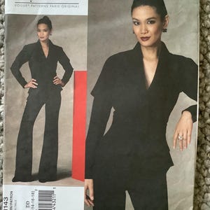 May include: A black Guy Laroche Vogue Patterns Paris Original sewing pattern. The pattern features a woman wearing a black suit with a V-neck jacket and wide-leg pants. The pattern number is V1143, and the size is DD (12-14-16-18).