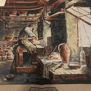 Può includere: Arazzo raffigurante un laboratorio di ceramica. Un artigiano lavora al tornio, circondato da strumenti e ceramiche finite. L'opera presenta una tavolozza di colori tenui di marroni, arancioni e grigi, con il testo "L'ATELIER DE POTERIES" in basso.