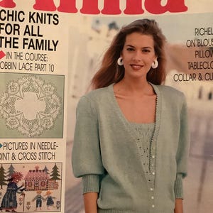 May include: A magazine cover featuring the title "Anna" in large red letters. The cover includes text about knitting and needlecrafts, with a woman wearing a light blue knit cardigan and top. The cover also features images of lace and cross-stitch projects.