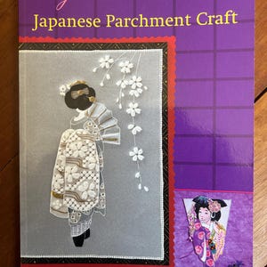 May include: A Pergamano Japanese Parchment Craft instructional book with a purple cover. The front features a white embossed illustration of a figure in a kimono with cherry blossoms, and a smaller inset image of a figure in a colorful kimono.