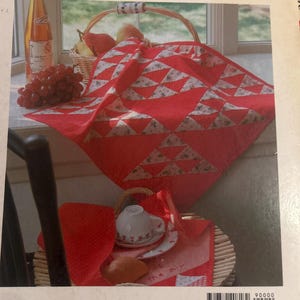Może przedstawiać: Książka pod tytułem Basic Patchwork with Patterns z czerwonobiałym geometrycznym quiltem na okładce. Okładka przedstawia czerwony quilt w tr&oacute;jkątne wzory, kosz z owocami, białą filiżankę na spodku oraz rogalik. ISBN 0-87040-818-6.