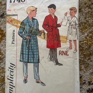 Op de afbeelding: Vintage Simplicity naaipatroon nummer 1740, maat 10, voor een badjas. Het patroon toont drie jongens die verschillende badjassen dragen, een in ruitjes, een in rood en een in wit.