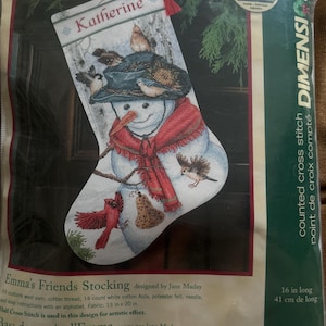 May include: A Dimensions counted cross stitch kit for a Christmas stocking titled Emma's Friends Stocking. The design features a snowman wearing a dark hat and red scarf, surrounded by various birds, with the name Katherine printed at the top.
