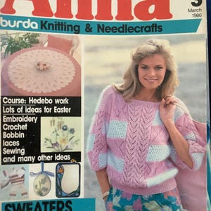 May include: A vintage magazine cover titled "Anna" featuring a woman wearing a pink and blue patterned sweater. The cover also includes text about knitting, needlecrafts, and Easter ideas. The magazine is dated March 1986.