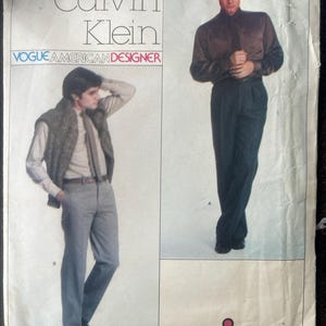 Könnte beinhalten: Eine Schnittmusterhülle für das Calvin Klein Vogue American Designer Schnittmuster 2256. Die Vorderseite zeigt zwei Illustrationen von Outfits: eines mit dunklem Hemd und Hose sowie ein weiteres mit hellem Hemd, Krawatte, strukturierter Weste und grauer Hose.