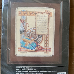 Könnte beinhalten: Ein Bucilla Kreuzstich-Set mit dem Titel "Walk In My Moccasins". Das Design zeigt ein indianisches Thema mit einem Zitat und einem detaillierten Bild von Mokassins und Federn. Das Set misst ca. 28,6 cm x 36,8 cm.