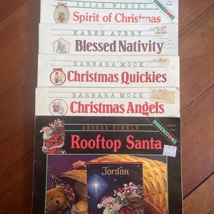 May include: A collection of Christmas-themed books, including "Frolicking Friends" and "Rooftop Santa." The books display festive illustrations and titles, with price stickers in US dollars visible on some of the books.