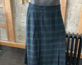 May include: A green and blue plaid skirt with pleats. The skirt is knee-length and has a straight silhouette.