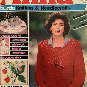 May include: Cover of "Anna" magazine, August 1986 issue, featuring a woman in a red sweater. The magazine cover includes text about knitting, needlecrafts, and crochet. The cover also features a table setting and cross-stitch designs.