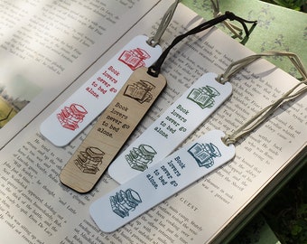 May include: Four bookmarks with the phrase "Book lovers never go to bed alone." The bookmarks are white, wood, and coloured with red, green, and blue ink. Each bookmark has a string attached.