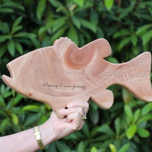Puede incluir: Tabla de cortar de madera con forma de pez con una regla y el texto "Wishing I was fishing" grabado en la superficie.