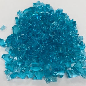May include: A pile of turquoise blue glass pieces. The glass pieces are irregular in shape and size.