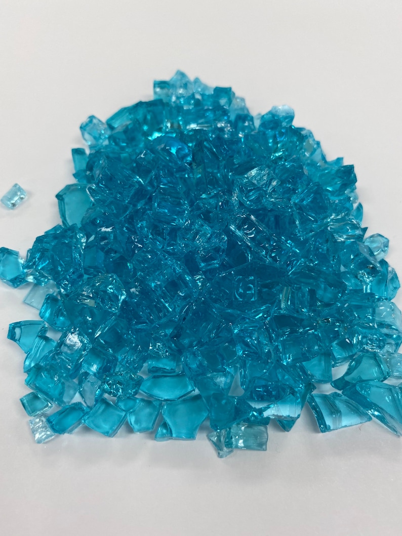 May include: A pile of turquoise blue glass pieces. The glass pieces are irregular in shape and size.