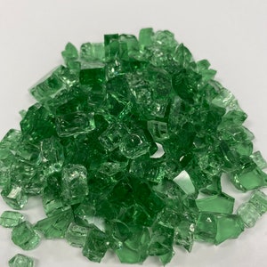May include: A pile of green glass fire pit gems. The gems are small, irregular pieces of glass that are used to create a decorative and colourful fire pit.