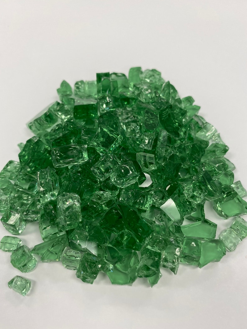 May include: A pile of green glass fire pit gems. The gems are small, irregular pieces of glass that are used to create a decorative and colourful fire pit.