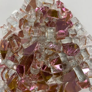 May include: A pile of iridescent glass pieces in shades of pink, gold, and clear. The glass pieces are irregular in shape and size, and they have a reflective surface.