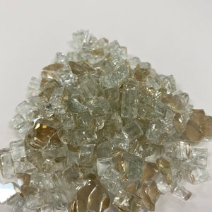 May include: A pile of clear and amber glass fire pit gems. The gems are small, irregular pieces of glass that are used to decorate fire pits.
