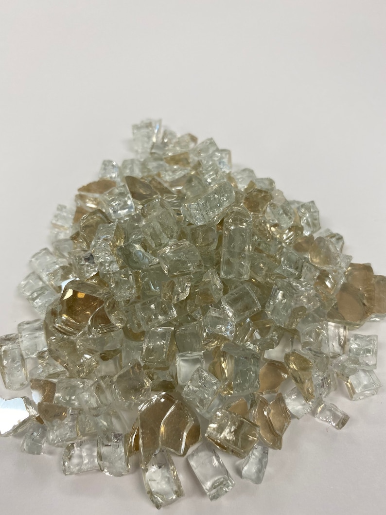 May include: A pile of clear and amber glass fire pit gems. The gems are small, irregular pieces of glass that are used to decorate fire pits.