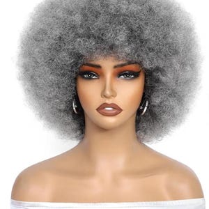 May include: A gray afro wig with a voluminous, curly texture. The wig is styled on a mannequin head with makeup, including dark eye shadow and hoop earrings. The mannequin is wearing a silver, off-the-shoulder top.