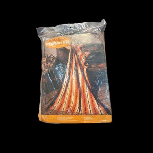 May include: A sealed plastic package containing a Malina afghan kit for crochet. The packaging features an orange oval logo with the text Malina afghan kit, and an image of a finished orange, yellow, and brown striped afghan with fringe.